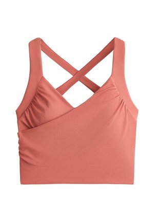 Mekan ružičasti kroj top na bretele s širokim križnim naramenicama i naboranim bočnim stranama na bijeloj pozadini.