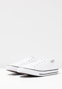 Hvite lerrets sneakers med runde tær, svarte striper og seks øyehull for snøring. Gummisåler med mønster for godt grep.