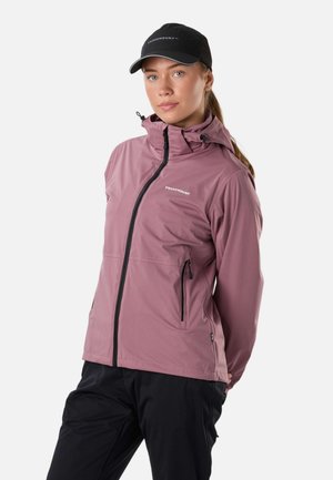 Kobieta ubrana w fioletowo-różową kurtkę na zamek z kapturem i czarną czapkę, stojąca na gładkim białym tle.