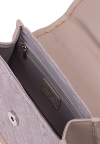 Beige quiltet taske med glat læderkant, der har en sølvknap og en lynlås lomme indeni, foret med gråt stof.