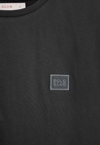 Svart t-shirt i smidigt tyg med rund halsringning och en liten broderad "POLO CLUB"-logotyp i grått på bröstet.