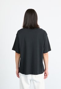 Black short-sleeve t-shirt, made of soft fabric, features a relaxed fit and rounded neckline. Simple design, no patterns or embellishments.