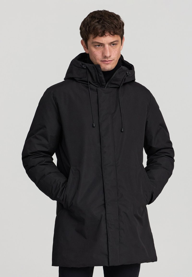 Parka nera imbottita con cappuccio regolabile, chiusura frontale con zip e tasche laterali. Texture liscia e design minimalista.