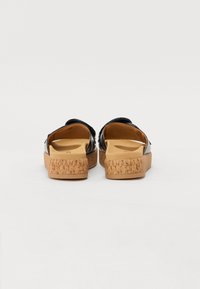 Sandales noires avec semelles en liège. Tige en cuir lisse avec un design minimaliste. Talon plat, arrière ouvert et large sangle pour plus de confort.