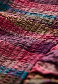 Tessuto testurizzato in diverse tonalità di rosa, viola e verde, caratterizzato da un motivo ondulato trapuntato. Aspetto morbido e stratificato.