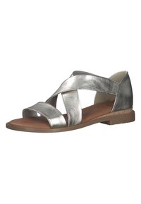 Sandal in argento metallico con design a strappi incrociati, punta aperta e suola bassa marrone. Texture liscia con una leggera lucentezza.