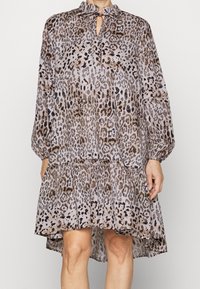 Šaty s leopardím potiskem vyrobené z lehké látky, s výstřihem ve tvaru klíče, volánkovým límcem, dlouhými rukávy a stupňovitým lemem.