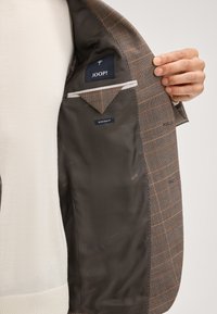 Szary-brązowy w deseń kraty żakiet wewnętrzny o gładkiej fakturze, z górną kieszenią i metką "JOOP!", oznaczony jako "Extra Slim Fit".