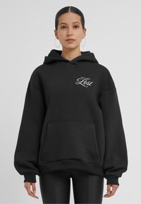 Felpa nera oversize con tasca frontale, cappuccio con coulisse e testo bianco che recita "LET'S GET Lost" sul petto. Tessuto morbido.