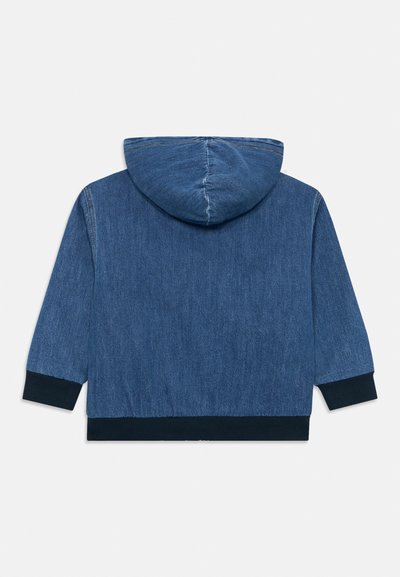 Moletom de denim azul médio com capuz ajustável. Apresenta uma textura suave e punhos em malha azul-marinho. A vista traseira mostra detalhes de costura mínimos.