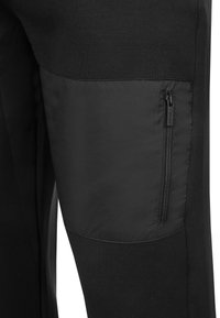 Czarne spodnie wykonane z teksturowanej bawełny z gładkim panelem z nylonu, wyposażone w boczną kieszeń na zamek.