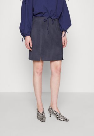 Navyblauw gestreepte rok met een split aan de voorkant, gecombineerd met zwart-witte zebra-print hakken. Textuurstof, taillebanden en een aansluitend ontwerp.