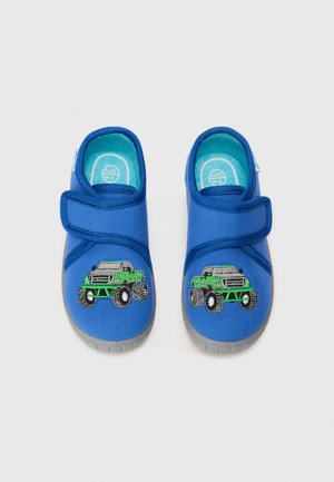 Blue slip-on shoes with a fabric upper, featuring a green monster truck design. Velcro strap and grey rubber sole complete the look.