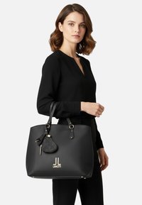 Borsa tote sintetica nera con texture in rilievo, dettagli in metallo tono oro e logo; dotata di due manici e accessorio portachiavi staccabile.