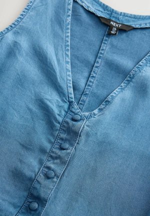 Kergelt sinine teksastopp, millel on V-kaelus, nupuga eesosa ja pehme, tekstuuriga kangas. Lihtne disain ilma mustriteta.