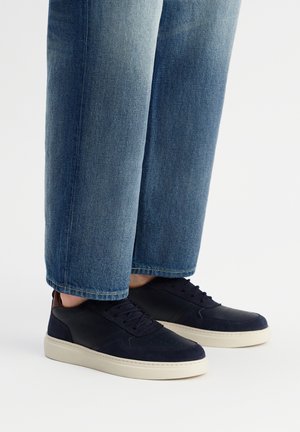 Granatowe sneakersy z połączeniem gładkiego i zamszowego materiału, z kremową gumową podeszwą i subtelnymi perforacjami zapewniającymi oddychalność.