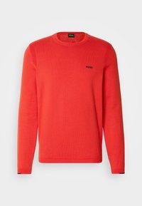 Pull rouge à manches longues avec col rond, poignets côtelés et logo « BOSS » sur le côté gauche de la poitrine, sur fond blanc uni.