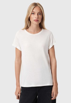 Kortærmet hvid t-shirt i let, struktureret stof med rund halsudskæring og afslappet pasform, parret med mørke jeans.