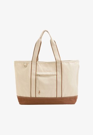 Ampia borsa tote in tela beige con base marrone, doppi manici, tasca frontale con coulisse e anello metallico sul lato.
