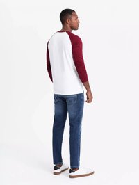 Weißes und burgunderrotes Langarmhemd mit Raglanärmeln, kombiniert mit blauen Jeans und weißen Turnschuhen, von hinten betrachtet.