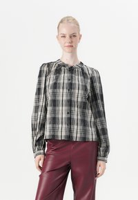 Zwart en beige geruite blouse met een verzamelde halslijn en lange mouwen, gecombineerd met glanzende bordeaux leren broek.