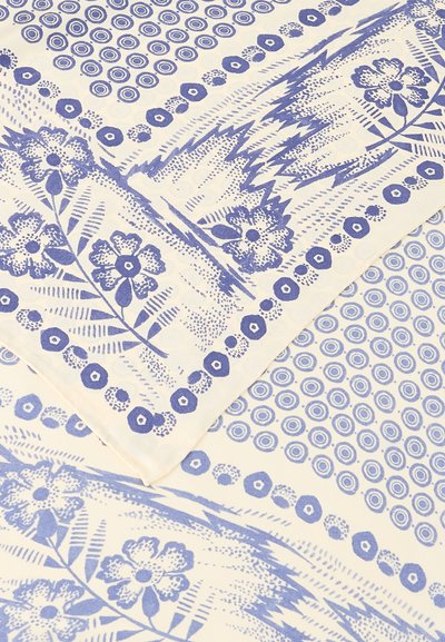 Λευκό ύφασμα με μπλε λουλουδάτα και κυκλικά γεωμετρικά σχέδια, που περιλαμβάνει λουλούδια, φύλλα και σειρές ομόκεντρων κύκλων σε επαναλαμβανόμενο μοτίβο.