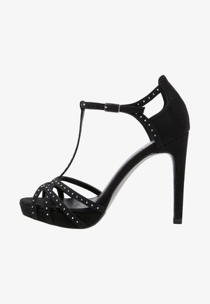 Sandal de tacón alto negro de material ante, con múltiples tiras entrecruzadas adornadas con pequeñas tachuelas y un diseño de tira en T.