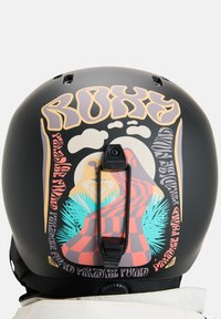 Čierna prilba s živou grafikou obsahujúcou abstraktné vzory v ružovej, žltej a modrej farbe. Obsahuje držák na kameru a ventilačné otvory.