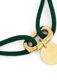 Corda verde intrecciata con una chiusura dorata e una medaglietta rotonda con la scritta "G P H STUDIO." La medaglietta presenta una superficie liscia e lucida con lettere in rilievo.