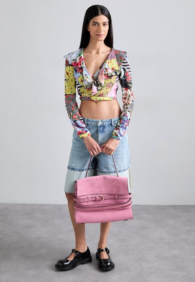 Maglioncino corto a maniche lunghe colorato e a fantasia con colletto arricciato, abbinato a una gonna di jeans chiara e una borsa in suede rosa, indossato con scarpe nere.