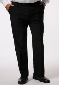 Pantalones de vestir negros con un diseño de pliegue, frente plano, bolsillos inclinados y una textura suave. Combinados con zapatos negros.
