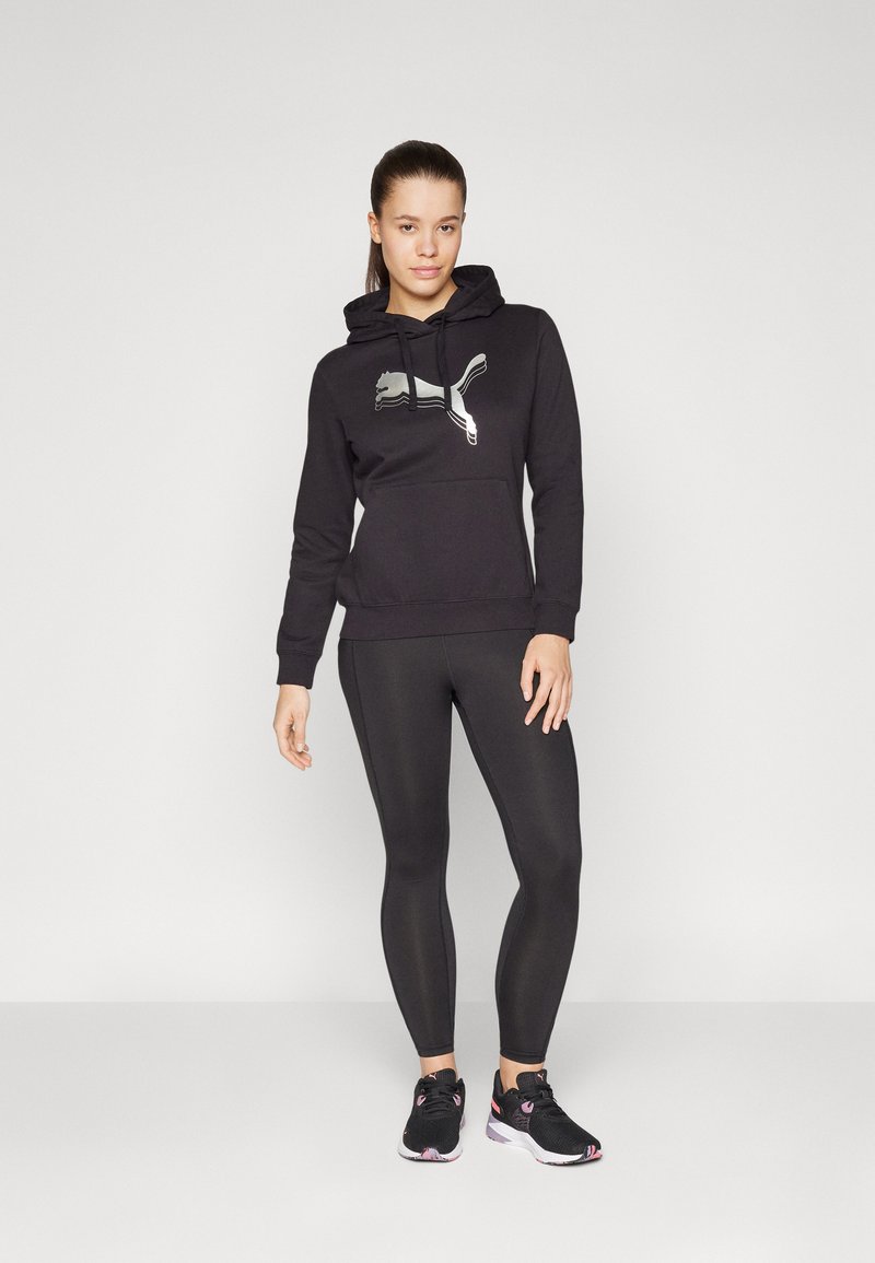 Schwarzer Hoodie mit grauem Puma-Logo, kombiniert mit schwarzen Leggings und schwarzen Sportschuhen mit pinken Akzenten. Glatter Stoff, lässige Passform.