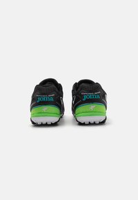 Scarpe da ginnastica nere con accenti verdi, tomaia in rete e suole in gomma bianca. Le caratteristiche includono dettagli di marca e superfici testurizzate.
