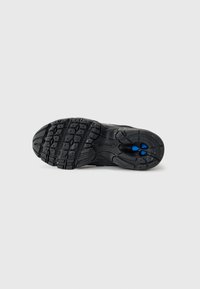 Schwarze Sportschuhsohle mit strukturiertem Gummioberfläche, ausgestattet mit einem Profilmuster für Grip und drei blauen Akzenten im Fersenbereich.