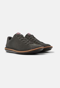 Gray suede sneakers with round toes, lace-up design, contrasting orange trim on the sole, textured rubber outsole, and red branding detail.