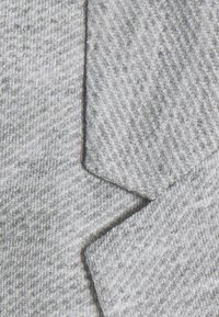 Grå texturerad tyg med ett diagonalt mönster, med en vikt kant för detaljer. Mjuk och slät yta som skapar visuell kontrast.