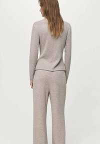 Ensemble gris en maille deux pièces comprenant un haut ajusté à manches longues avec col montant et un pantalon jambes larges, tous deux en tissu doux et texturé.