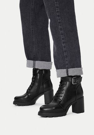 Czarne botki za kostkę na masywnym obcasie, wykonane z teksturowanej skóry, z przodem na sznurowadła, bocznym zamkiem i ozdobną klamrą przy kołnierzu.