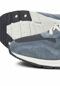 Blå ruskindsneakers med en tekstureret stofoverdel, rund tå og hvid mellemsål. Sålen har et udtalt dækmønster.