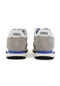 Zapatillas deportivas de ante gris con acentos en blanco y azul, que cuentan con una suela acolchada y una suela exterior de goma negra. "1968" impreso en el talón.