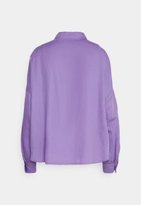 Chemise lavande à manches longues avec col, vue de dos, dotée de poignets boutonnés et d'une coupe ample.