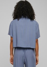 Blue striped cropped shirt with short sleeves, featuring a relaxed fit and smooth texture. Stripes alternate between dark blue and white.