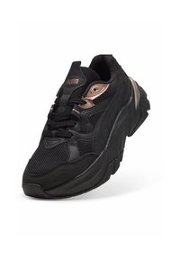 Baskets Puma noires avec semelle épaisse, tige en mesh et cuir, accents en or rose et fermeture à lacets.