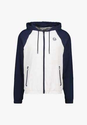 Capuchonjack met een witte body en marineblauwe mouwen, sluiting met rits aan de voorkant en twee zijzakken met rits. Zachte stofstructuur.