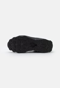 Suela de zapato deportivo negro con patrón de tracción de goma, tachuelas circulares y logotipo de Nike. Diseño plano, superficie texturizada para agarre.