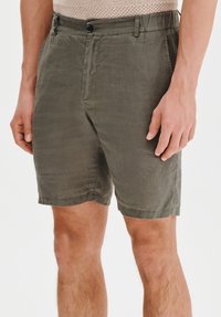 Oliwkowe szorty wykonane z lekkiego materiału, z zapięciem na guzik z przodu, kieszeniami bocznymi oraz luźnym krojem i prostym dołem.