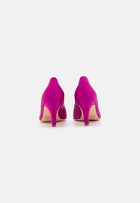 Scarpe con tacco alto fucsia con una texture liscia, design a punta e tacco stretto. Le suole sono di un colore chiaro con una leggera lucentezza.