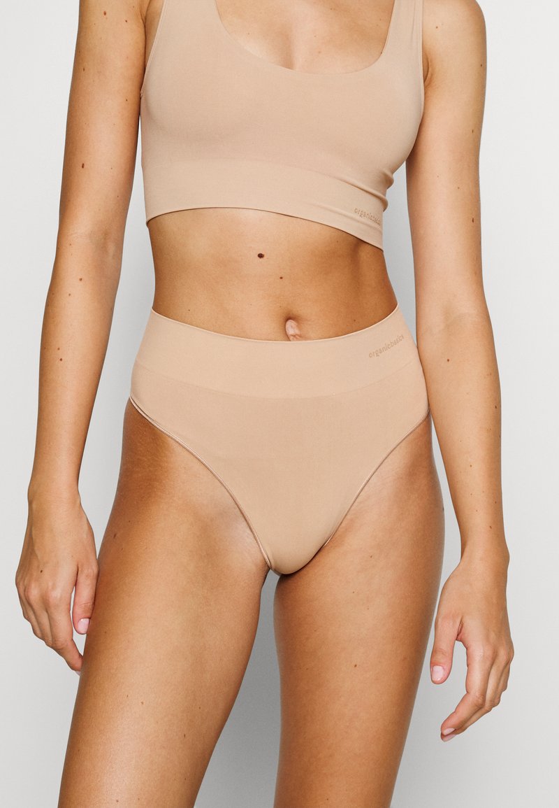 Beige high-waisted underwear and matching crop top made of smooth fabric. Features a seamless design with a subtle brand logo.