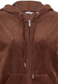 Sweat à capuche zippé marron doux avec cordons et poches avant, en tissu peluche pour chaleur et confort.