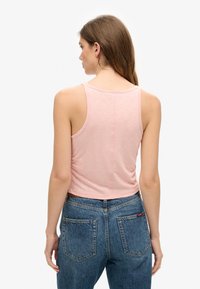 Roze cropped tanktop met een ronde halslijn en dunne bandjes, gecombineerd met high-waisted blauwe spijkerbroek met achterzakken.